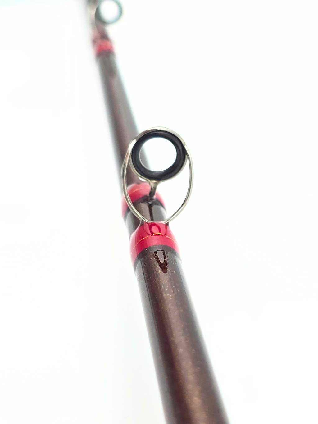 Gros plan sur un guide en acier inoxydable de la canne Chatterbeast avec ligature rouge et blank brun métallique scintillant.